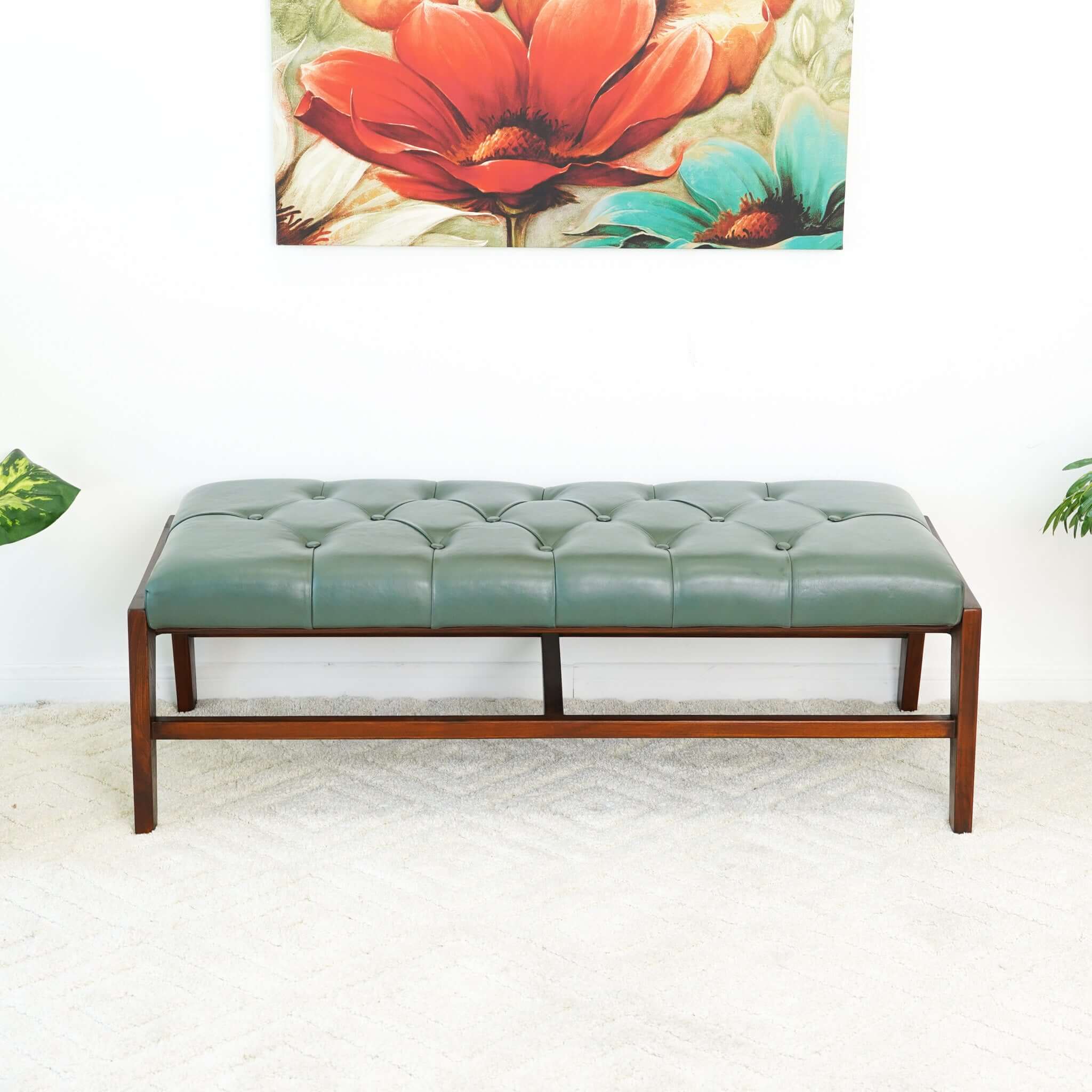A green leather bench with button detailing, set on a solid walnut wood frame.