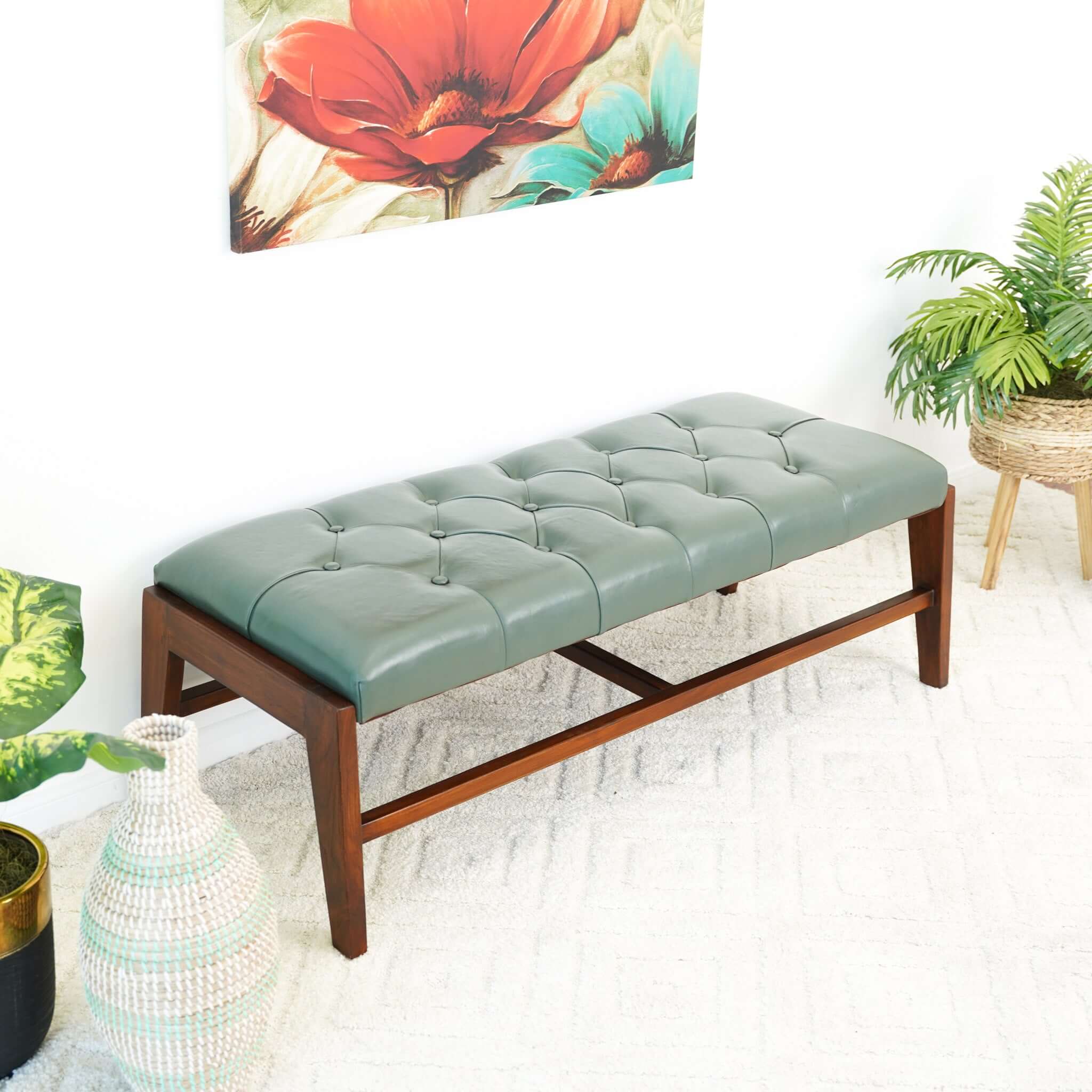 A green leather bench with button detailing, set on a solid walnut wood frame.