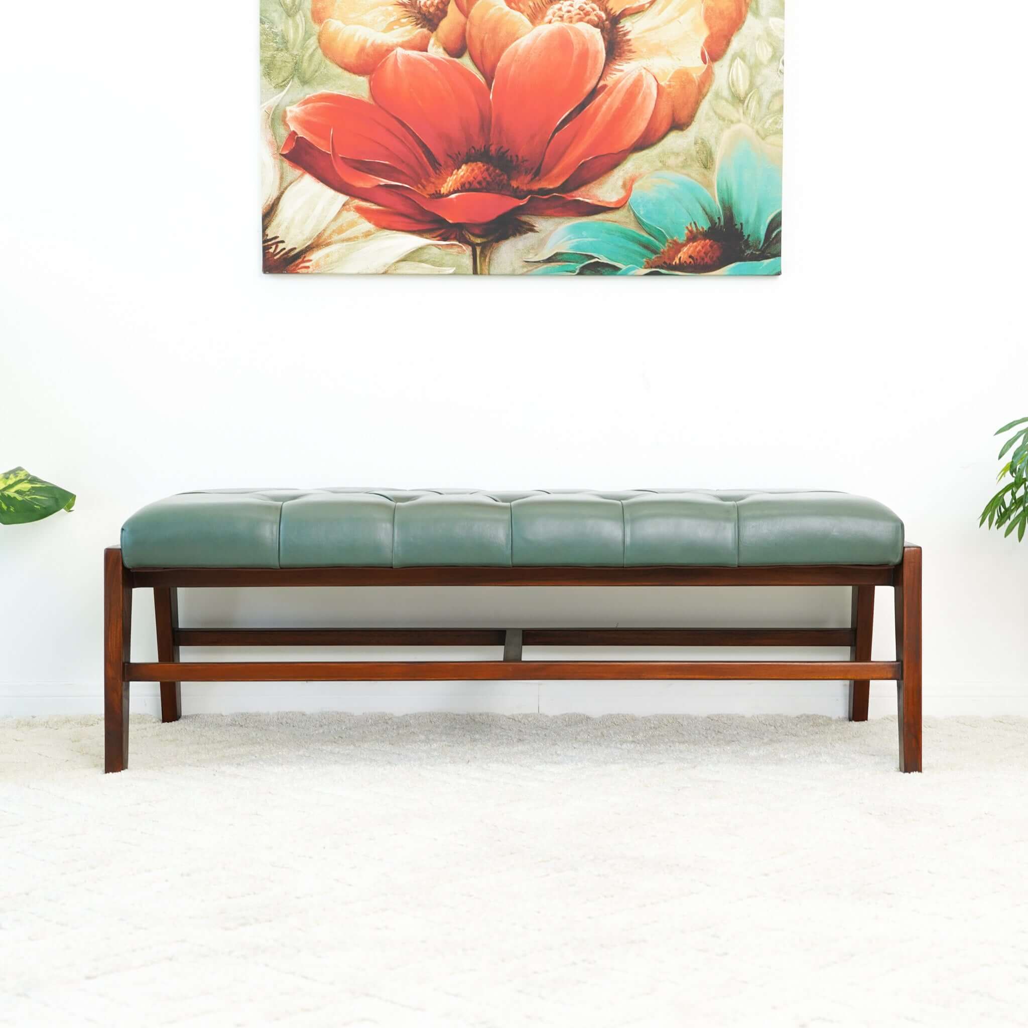 A green leather bench with button detailing, set on a solid walnut wood frame.